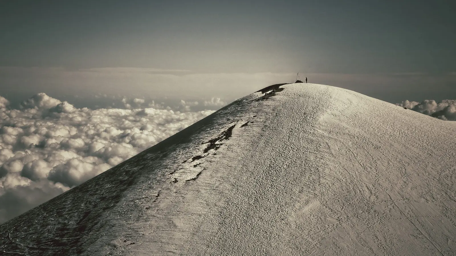 Lone climber on a snowy summit above a sea of clouds