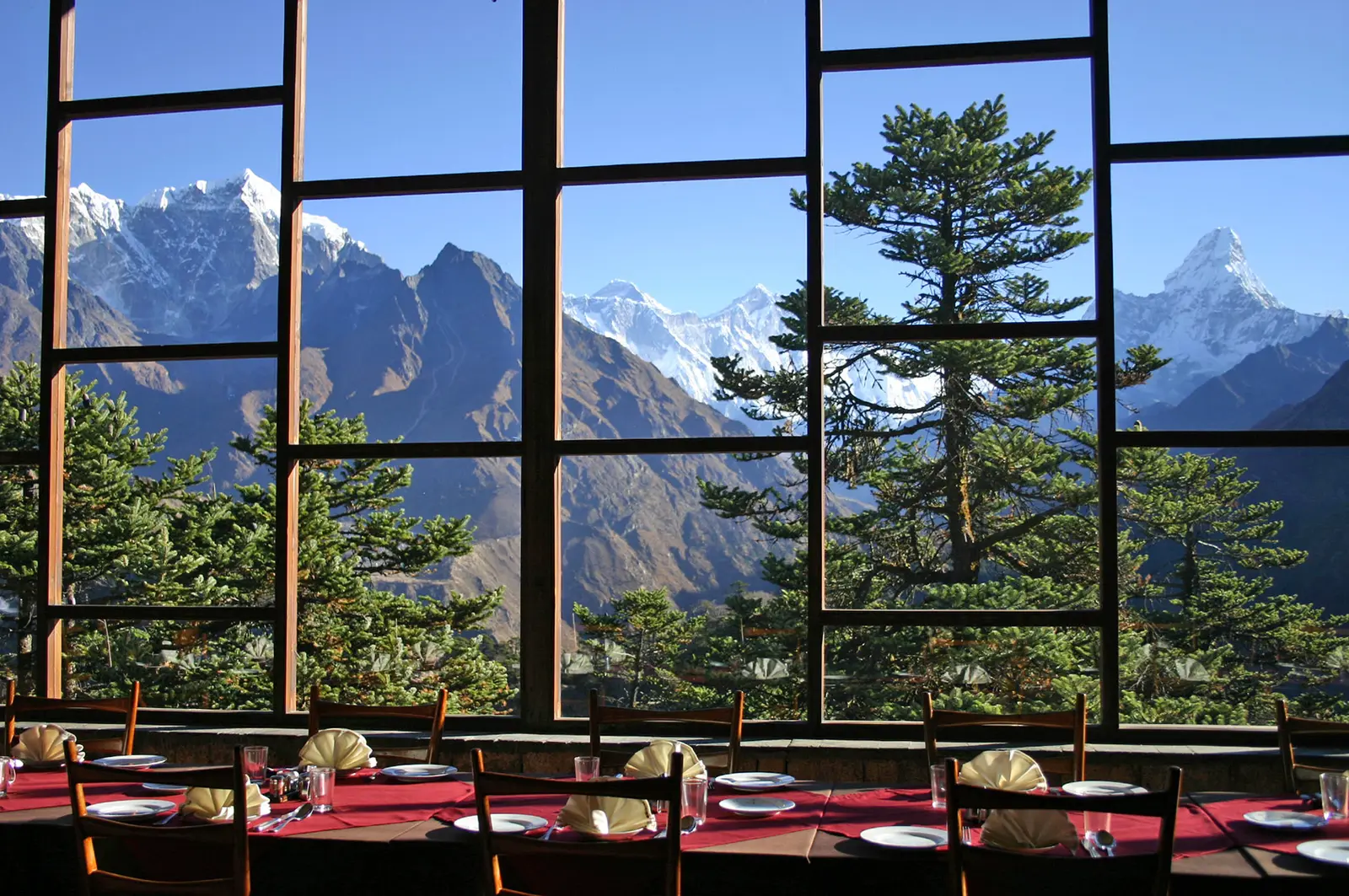 Dining room with set tables and large windows framing Everest and Ama Dablam mountain