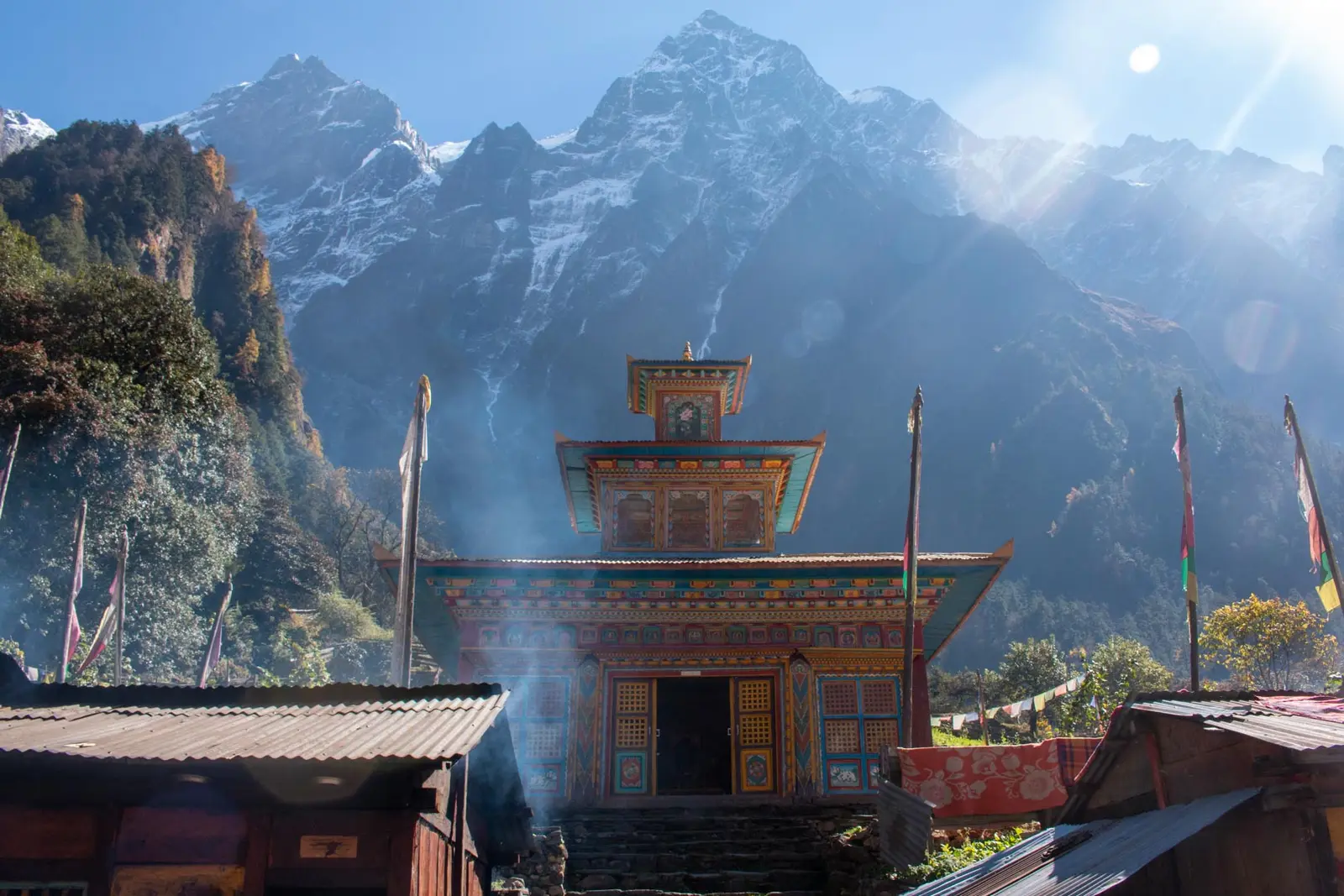 Painted monastery with a pagoda roof below forested mountains