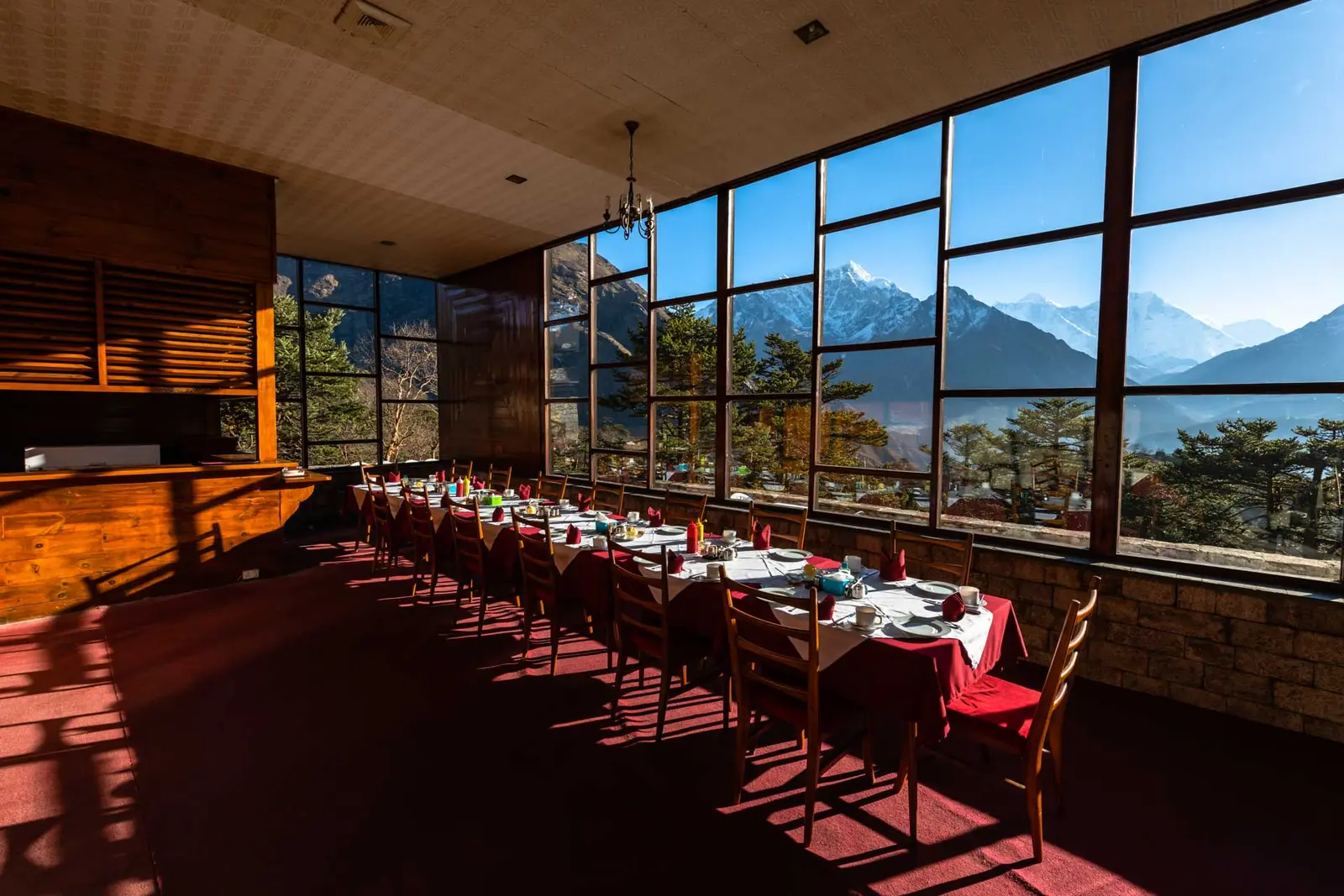 Hotel dining room with long tables and tall windows facing snowy mountains