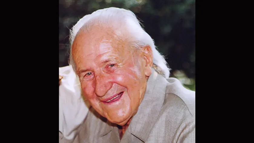 Smiling elderly man with white hair in a light jacket