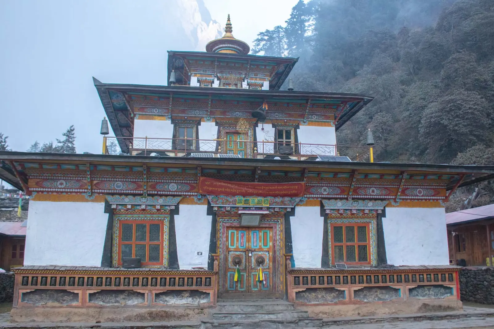 Painted facade of a monastery with carved windows and a gilded roof