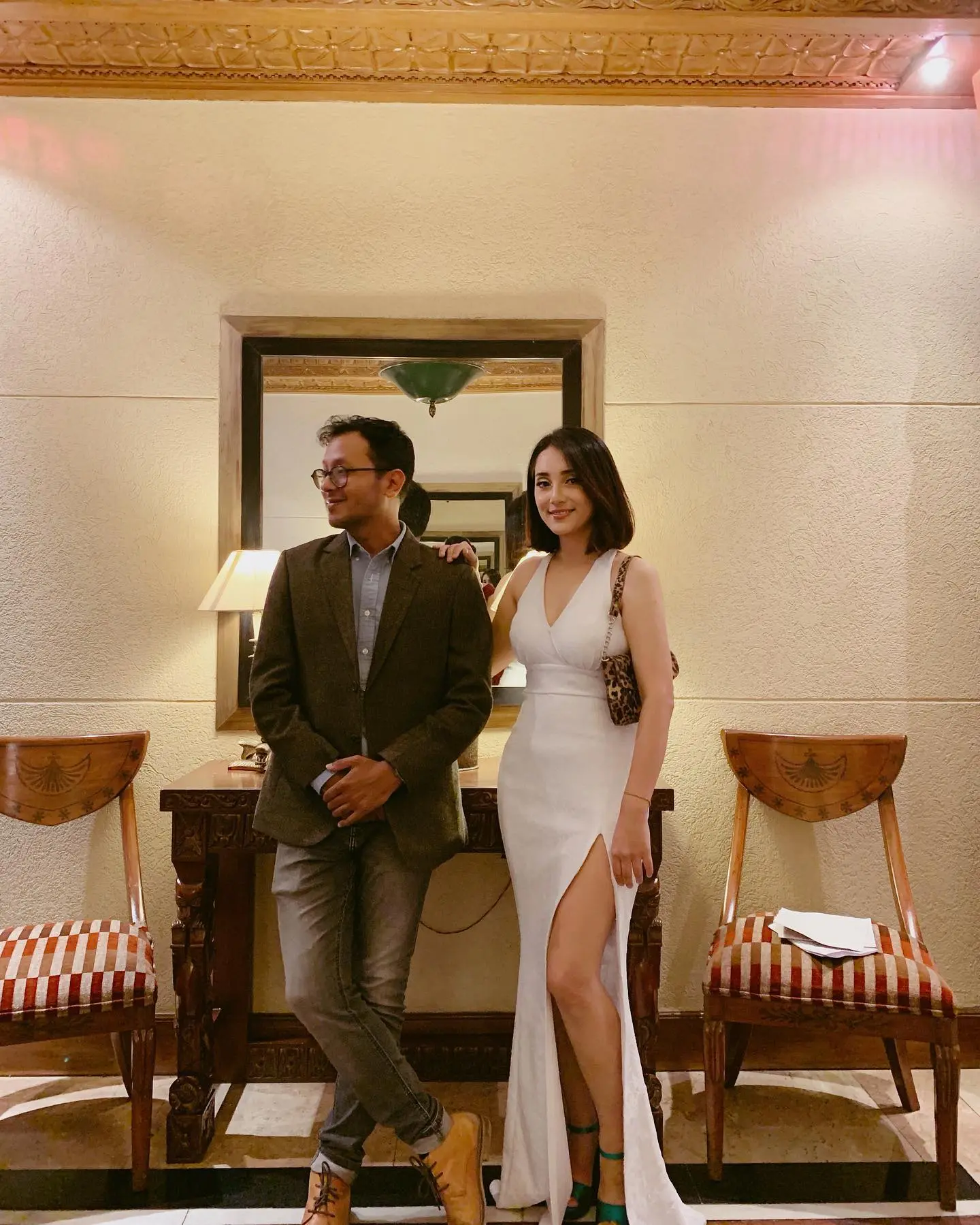 Man and woman in evening wear posing in a hotel corridor