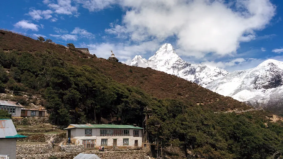 Ama Dablam mountain rising above forested slopes and stone houses at Pangboche