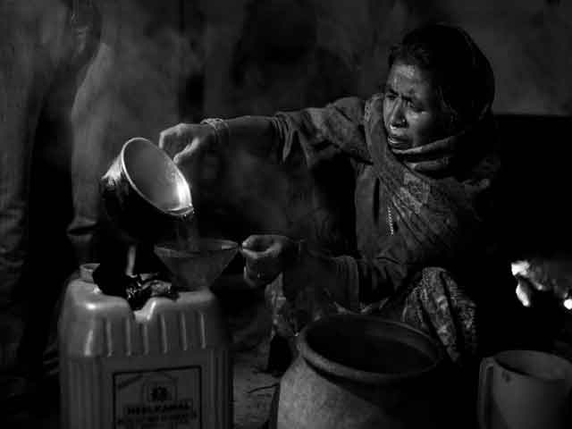 A women pouring Raksi in a vessel